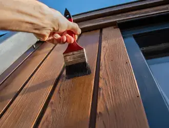Application de peinture sur une boiserie extérieure avec un pinceau.